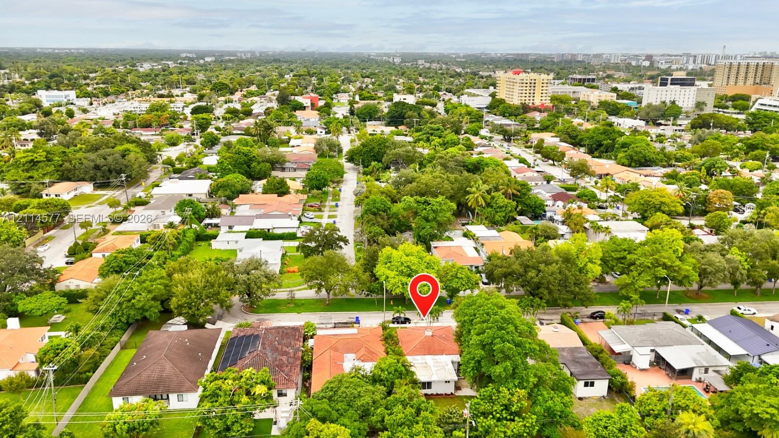 Aerial perspective of a residential property featuring a tiled roof, mature canopy trees, and established landscaping