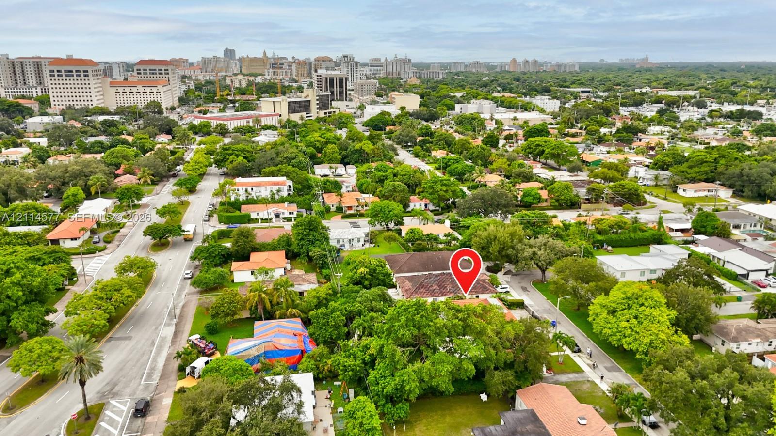 Aerial perspective of a residential property featuring a hipped roof, mature canopy trees, and established landscaping within a dense urban corridor