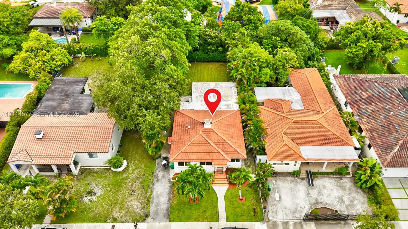 Aerial perspective of a residence featuring a terracotta-tiled roof, concrete chimney, paved walkway, and mature landscaping