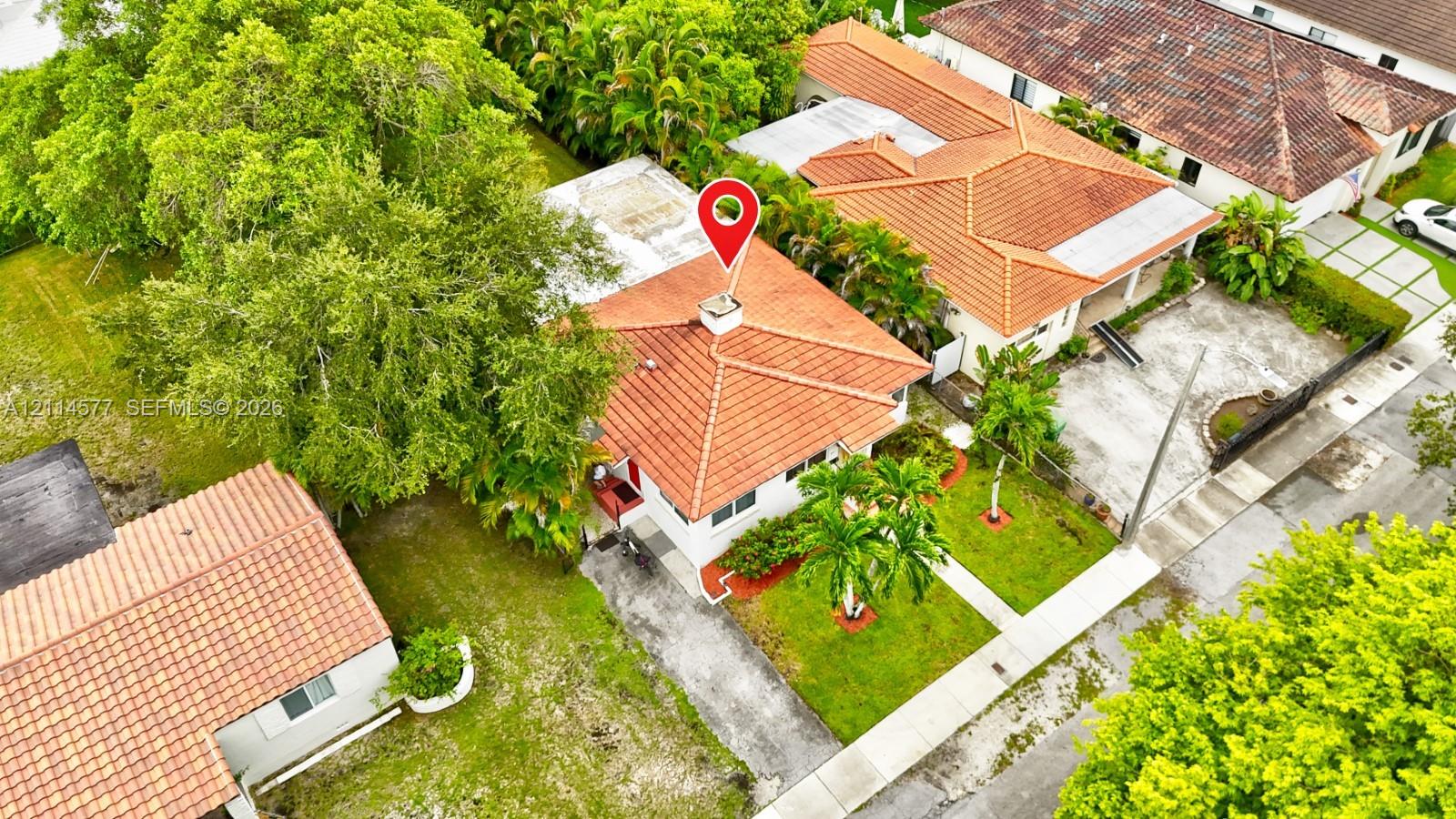 Aerial perspective of a detached residence featuring a clay tile roof, concrete driveway, and mature landscaping