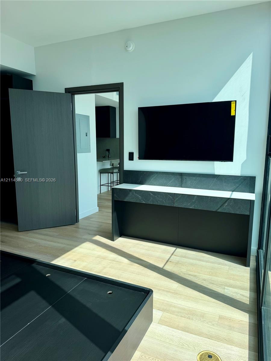 Custom built-in console featuring stone-finish surfacing, light wood-finish flooring, and dark-toned interior doors