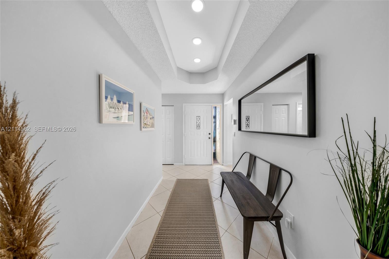 Entryway featuring tile flooring, a tray ceiling with recessed lighting, and a white paneled front door with decorative glass inserts