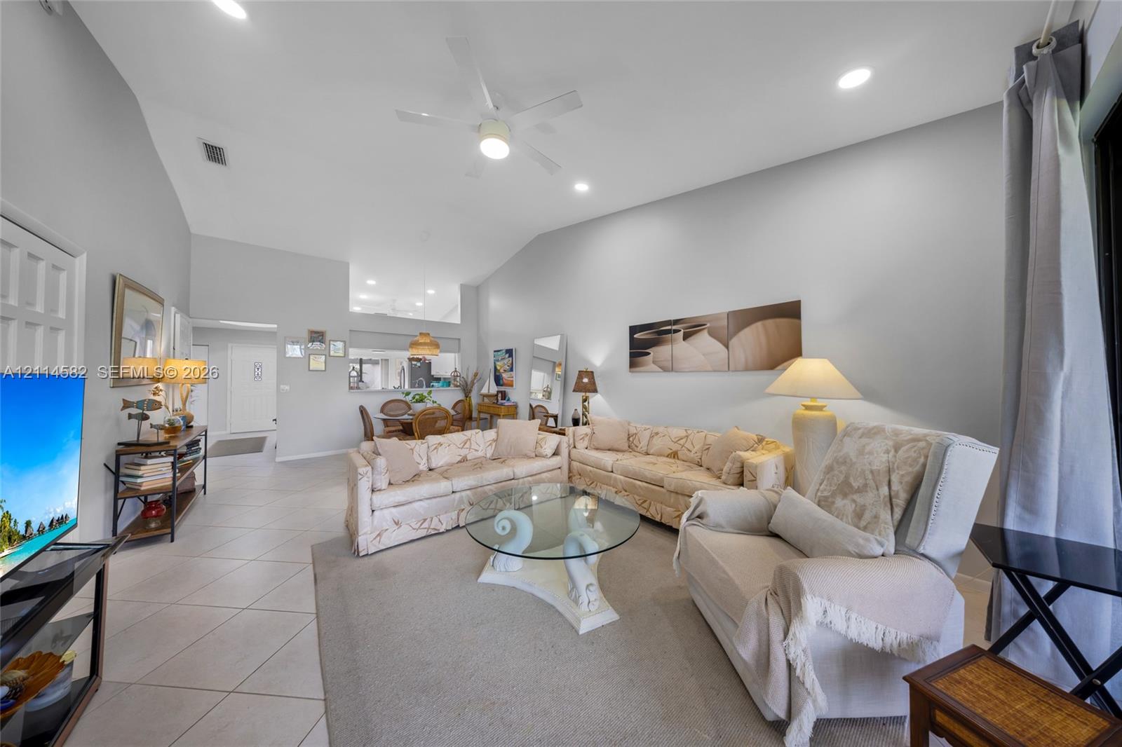 Vaulted ceilings, large-format tile flooring, recessed lighting, and a ceiling fan