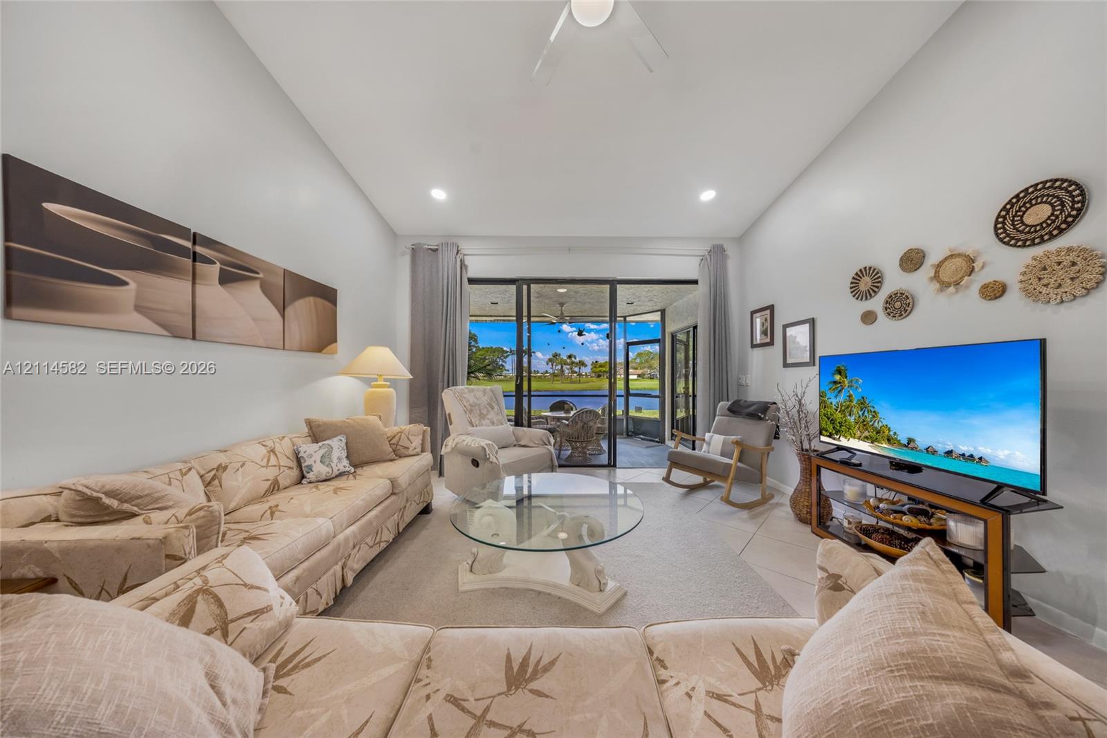 High-ceiling living area featuring recessed lighting, a ceiling fan, light-toned tile flooring, and oversized sliding glass doors