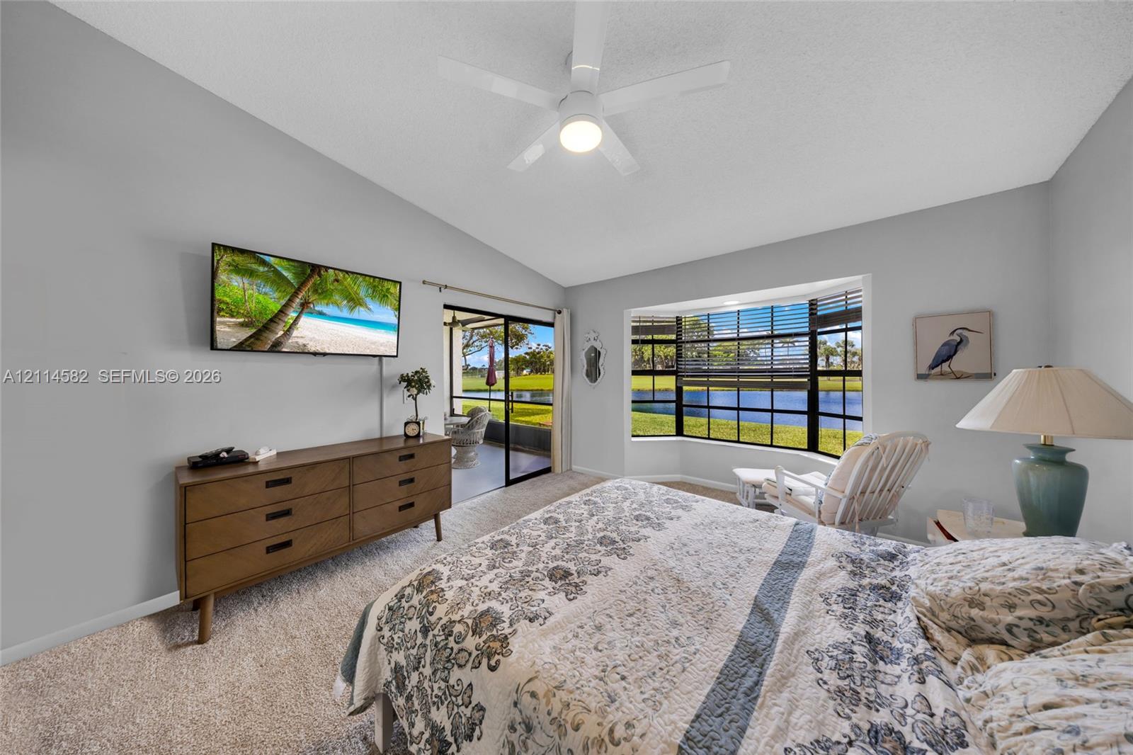 Vaulted ceilings with a central ceiling fan, expansive bay window, and sliding glass doors