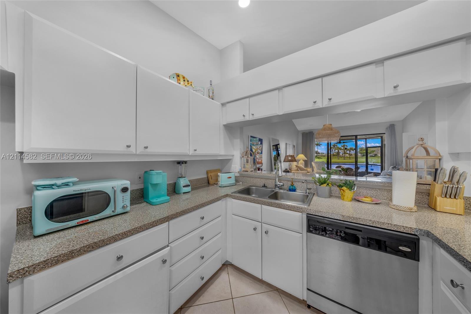 Kitchen featuring white cabinetry, stone-finish countertops, dual-basin stainless steel sink, and stainless steel dishwasher