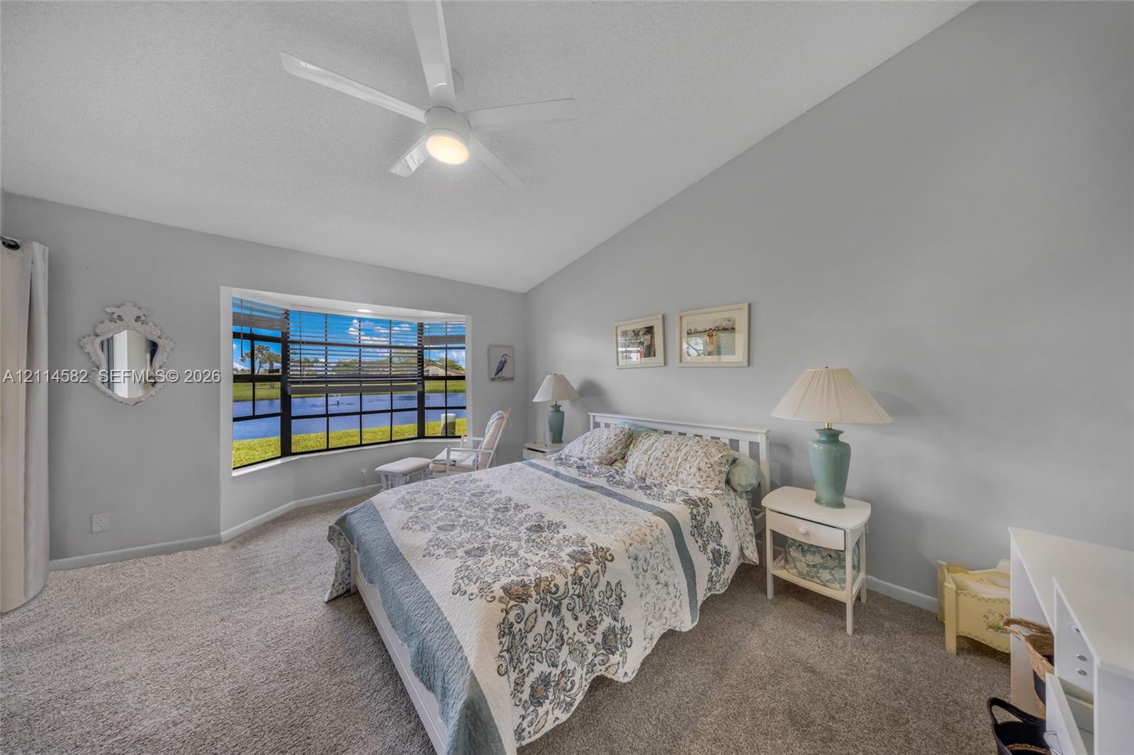 Bedroom with vaulted ceilings, large bay window, wall-to-wall carpeting, and a ceiling fan with integrated lighting