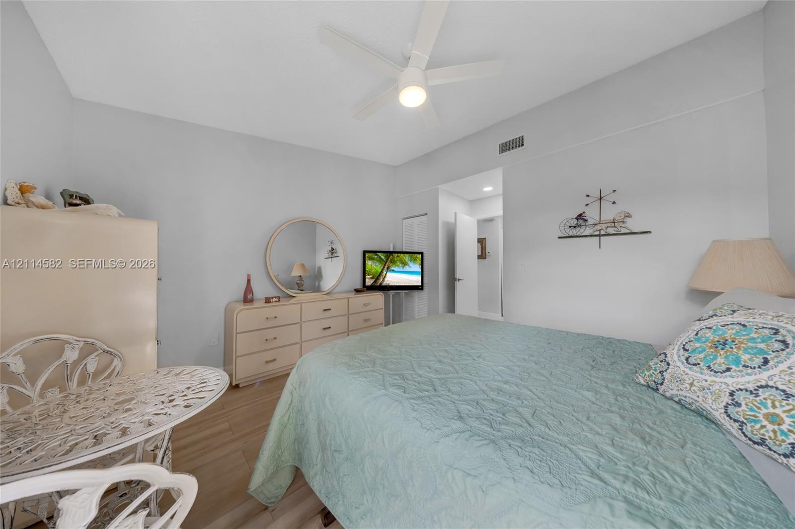 Neutral-toned walls, wood-finish flooring, and a white ceiling-mounted fan with integrated lighting