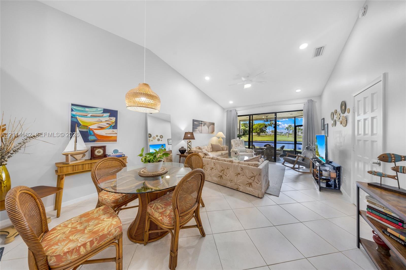 Vaulted ceilings, large-format tile flooring, recessed lighting, and expansive sliding glass doors leading to a screened lanai