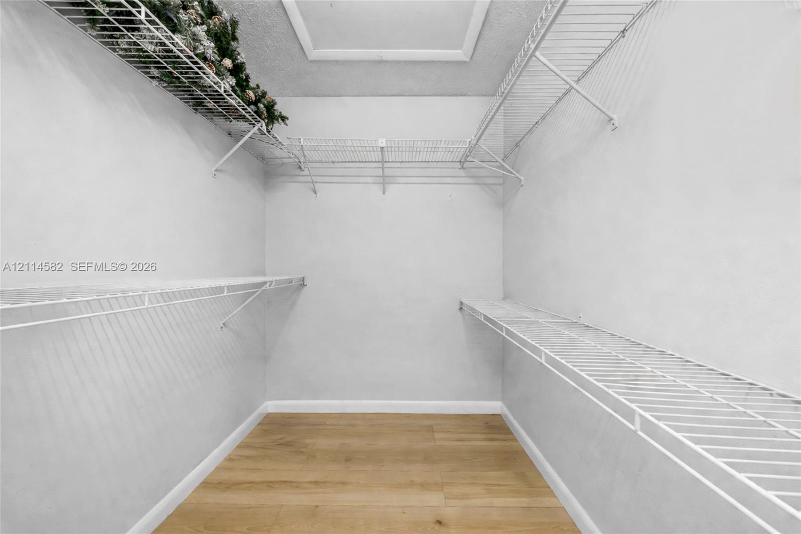 Walk-in closet featuring wood-finish flooring and tiered white wire shelving