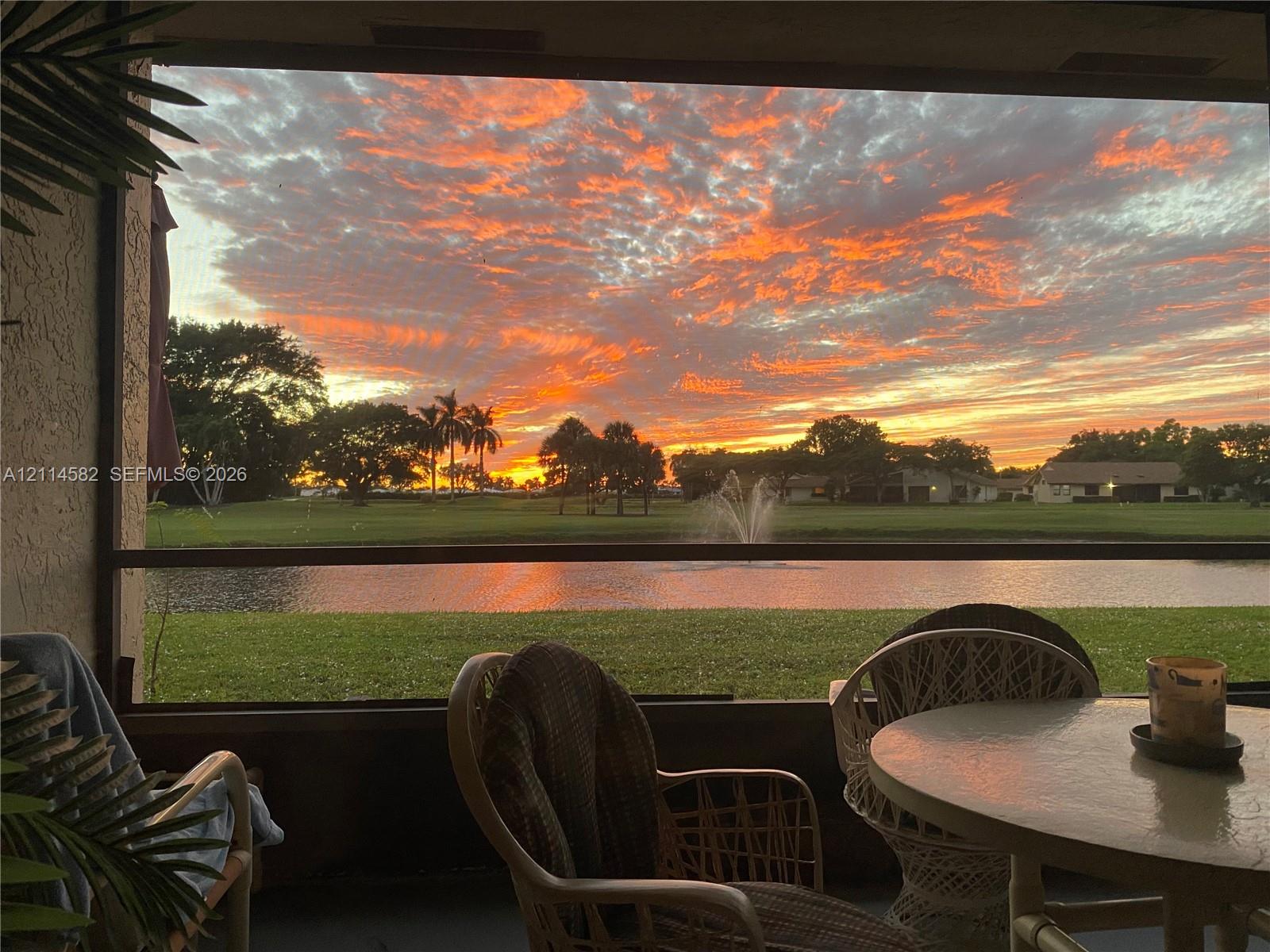 Screened lanai featuring an outdoor enclosure, water frontage with an integrated fountain, and a landscaped grass perimeter
