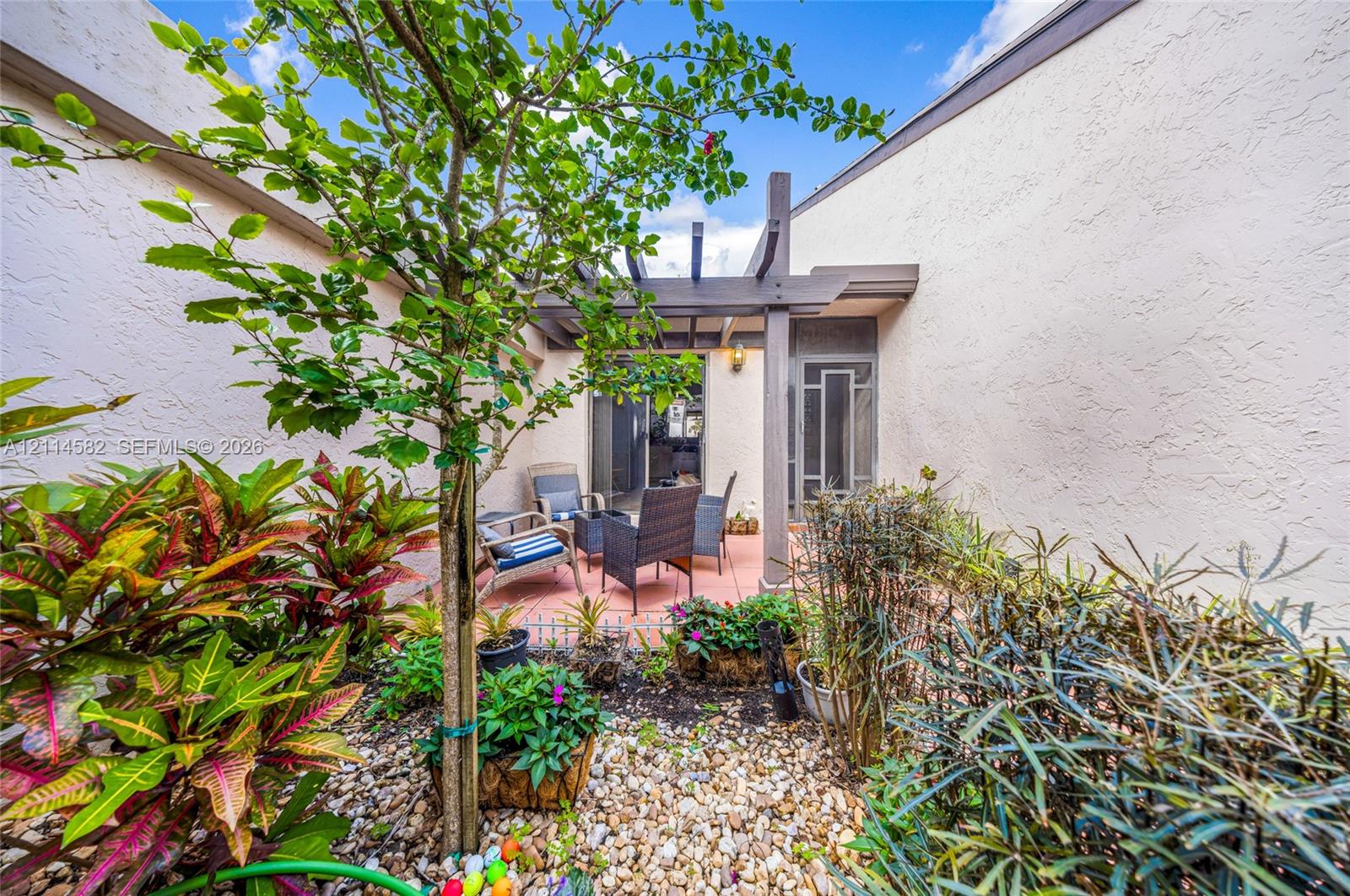 Enclosed courtyard featuring a pergola, tiled patio, and native landscaping with stone ground cover
