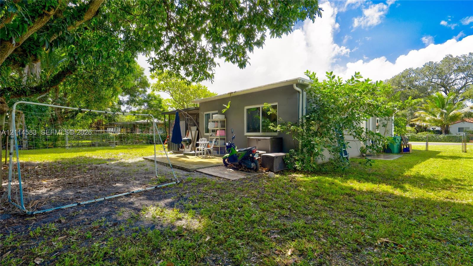 Expansive backyard featuring mature shade trees, a concrete patio, and perimeter fencing