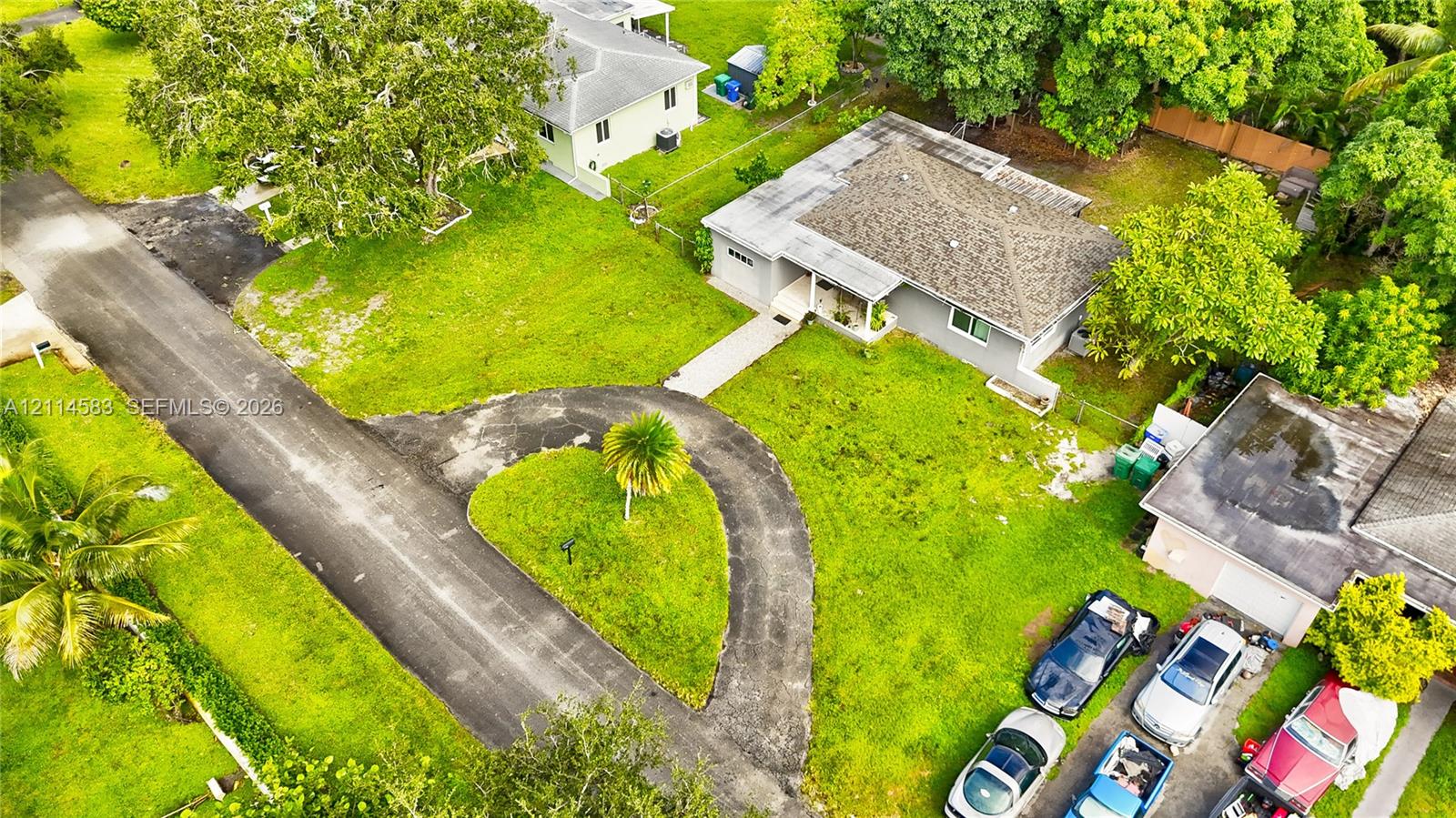 Aerial perspective of a single-story residence featuring a hipped roof, attached garage, paved circular driveway, and established landscaping Aerial perspective of a single-story residence featuring a hipped roof, attached garage, paved circular driveway, and established landscaping
