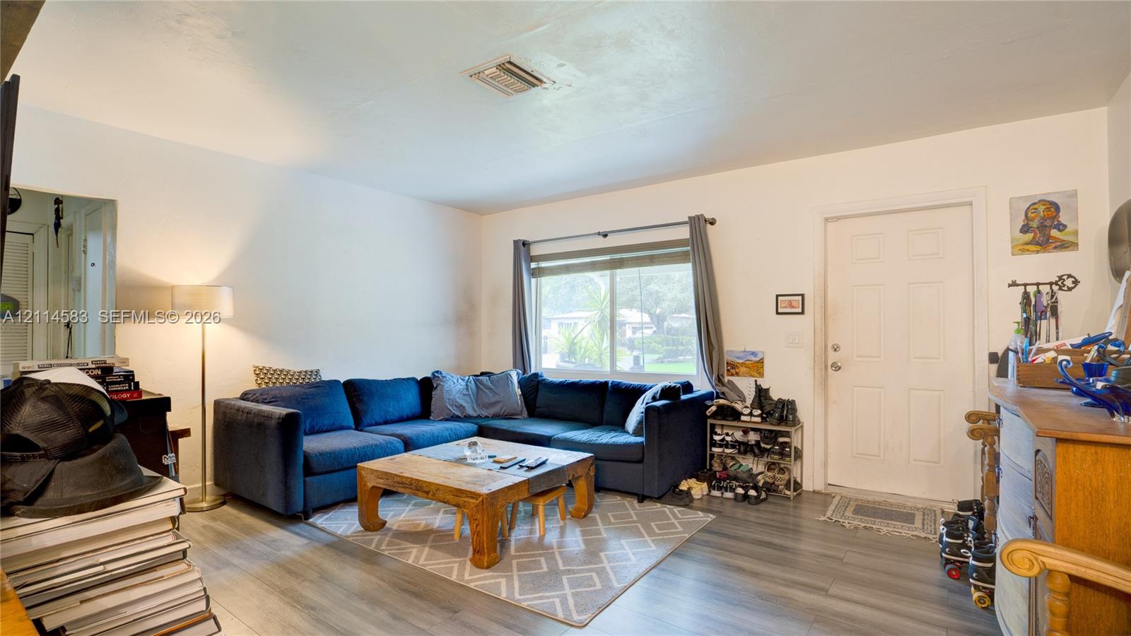 Living area featuring wood-finish flooring, a horizontal sliding window, and a panelled entry door