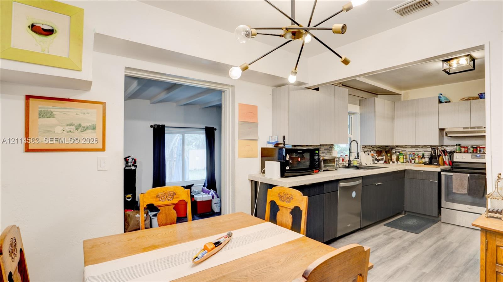 Kitchen featuring two-tone cabinetry, wood-finish flooring, a multi-arm Sputnik-style chandelier, and light-toned solid surface countertops