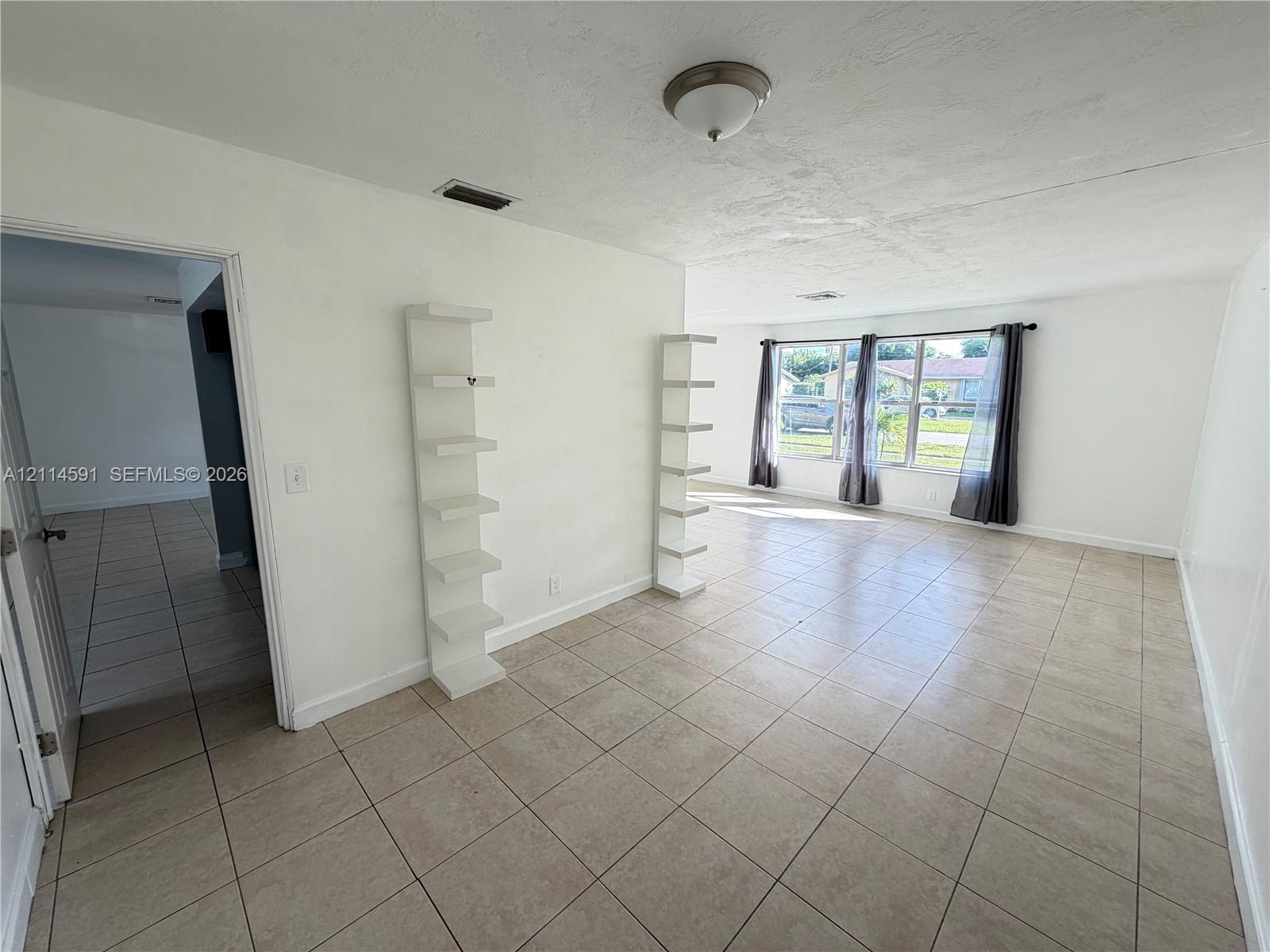 Open floor plan featuring tile flooring, built-in wall shelving, and large windows providing natural light