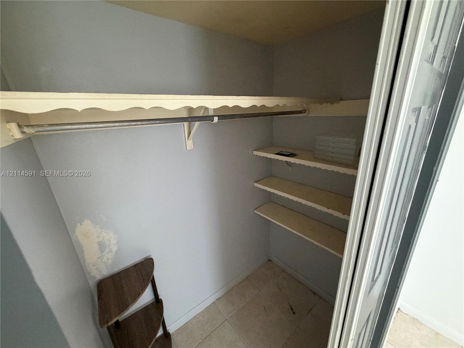 Closet featuring tile flooring, a built-in rod, and multi-tiered shelving