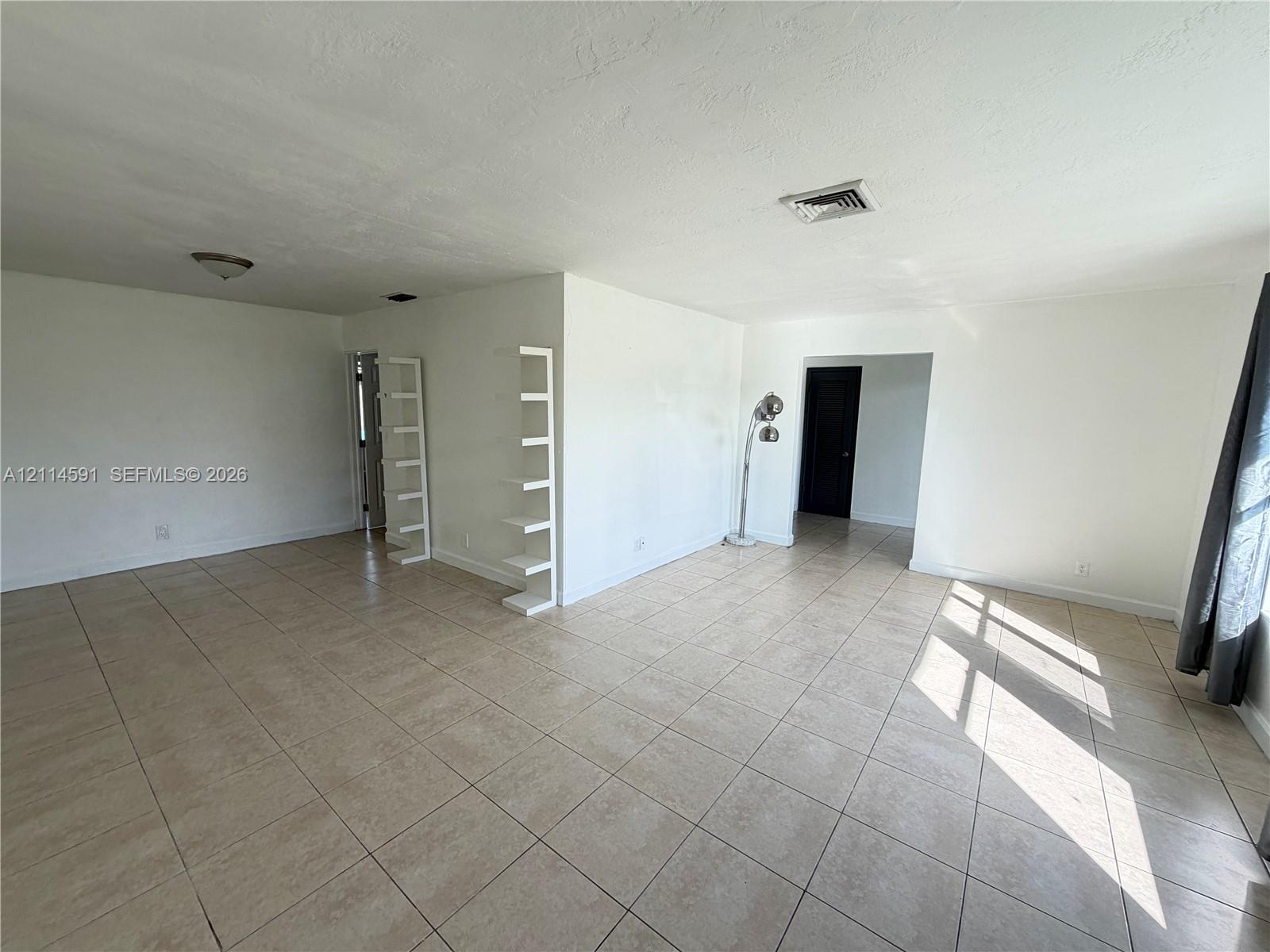 Neutral-toned ceramic tile flooring, built-in wall shelving, and recessed ceiling lighting