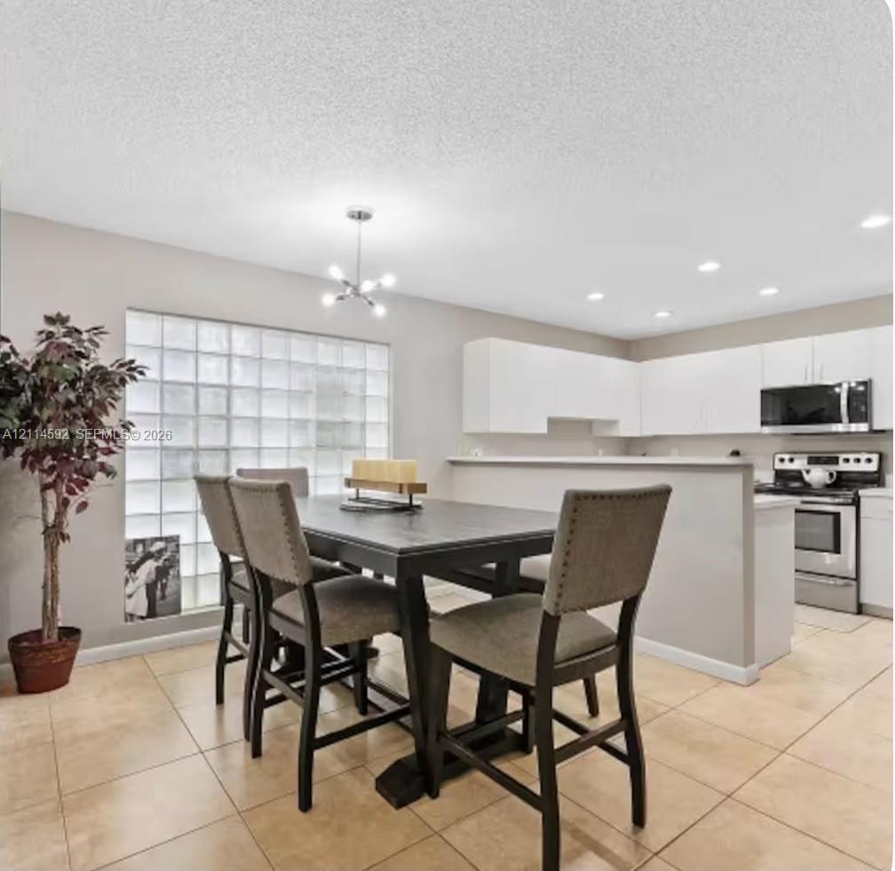 Kitchen featuring white cabinetry, stainless steel appliances, tile flooring, glass block window detailing, and recessed lighting Kitchen featuring white cabinetry, stainless steel appliances, tile flooring, glass block window detailing, and recessed lighting