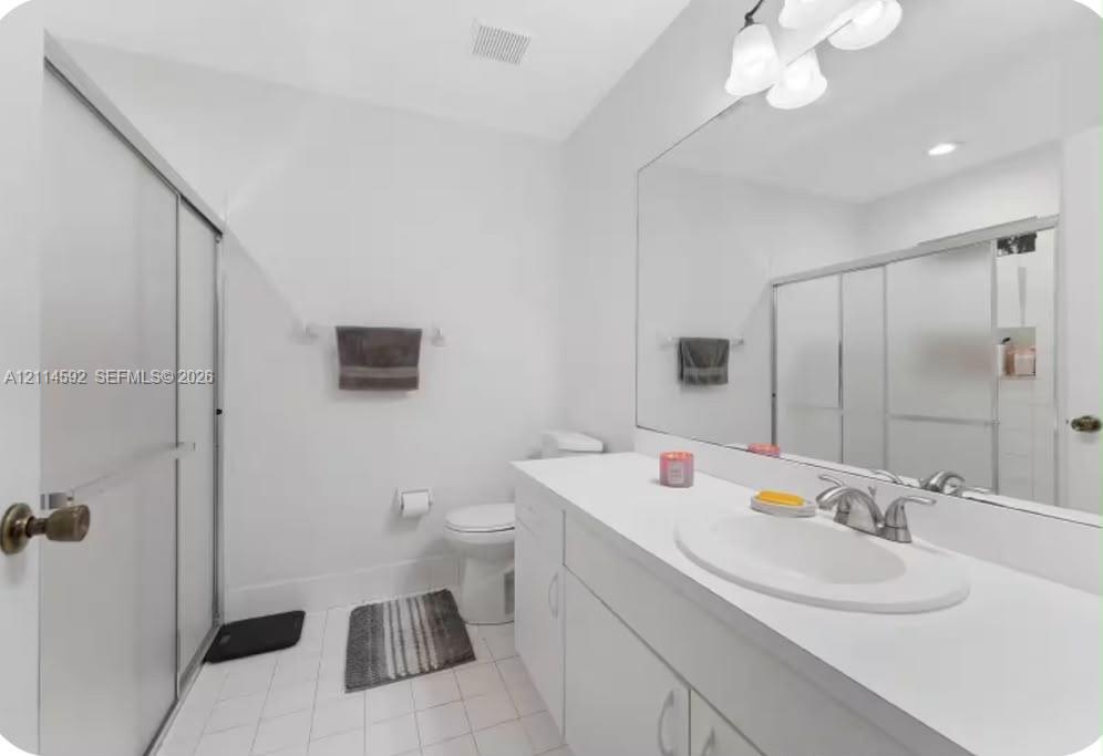 Full-width mirror, white cabinetry with solid-surface countertop, integrated vanity sink, brushed-metal faucet, and walk-in shower enclosure Full-width mirror, white cabinetry with solid-surface countertop, integrated vanity sink, brushed-metal faucet, and walk-in shower enclosure
