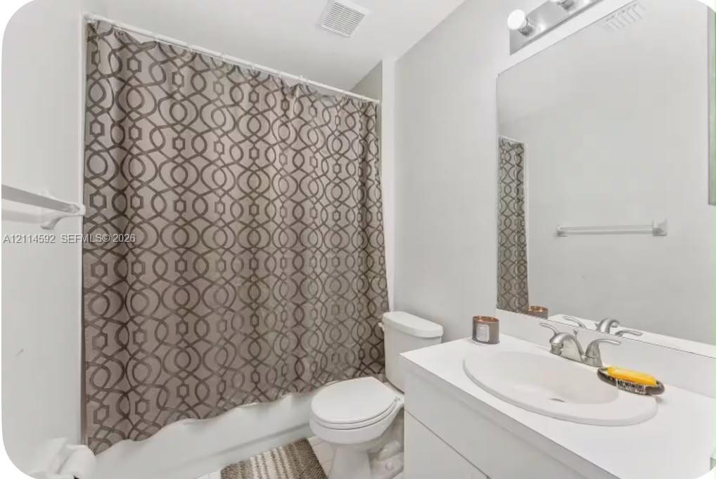 Bathroom featuring a white vanity with an integrated oval sink, chrome faucet, wall-mounted mirror, and a tub-shower combination Bathroom featuring a white vanity with an integrated oval sink, chrome faucet, wall-mounted mirror, and a tub-shower combination