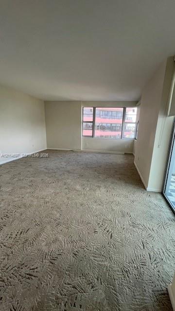 Spacious interior featuring patterned wall-to-wall carpeting and large windows with horizontal mullions