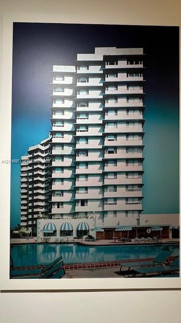 High-rise residential exterior featuring tiered structural balconies, a ground-level swimming pool, and striped retractable awnings