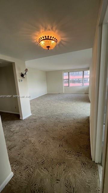 Interior space featuring wall-to-wall carpeting, an ornamental flush-mount chandelier, and a large multi-pane window
