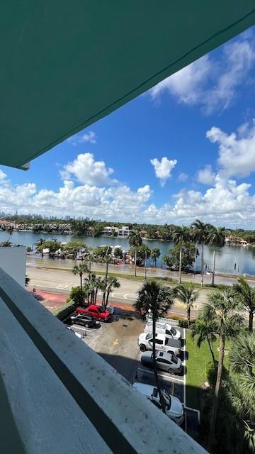Balcony featuring a concrete overhang with an expansive waterfront outlook and tropical landscaping