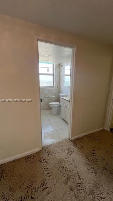 Bathroom featuring tile flooring, a built-in vanity cabinet with countertop, an integrated commode, and a window with a horizontal grid pattern
