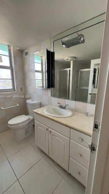 Bathroom featuring a white vanity cabinet with stone-finish countertop, oval undermount sink, expansive wall-to-wall mirror, and light-tone tile flooring