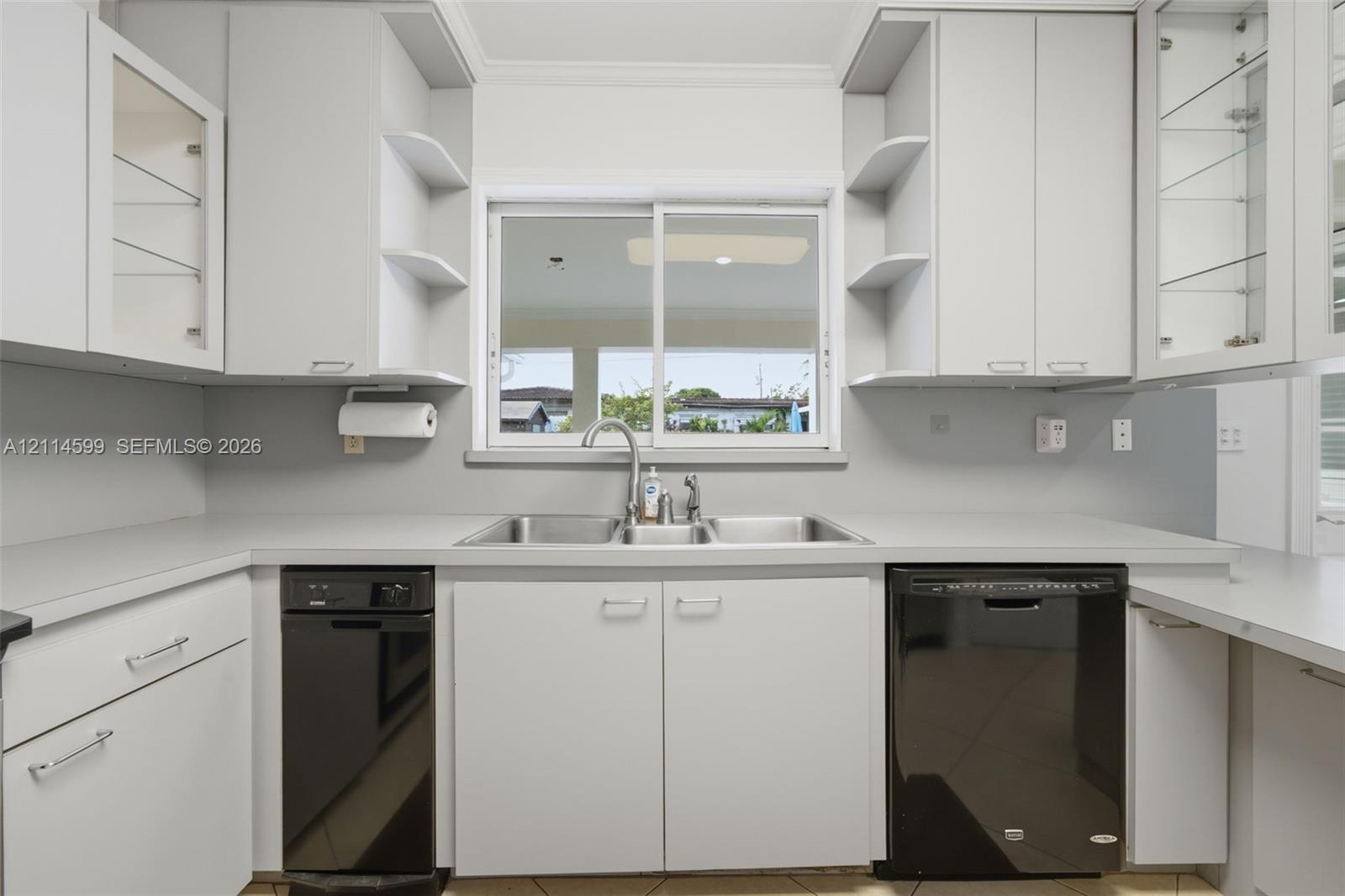 Kitchen featuring flat-panel cabinetry, open shelving, dual-basin stainless steel sink, solid-surface countertops, and contrasting black appliances