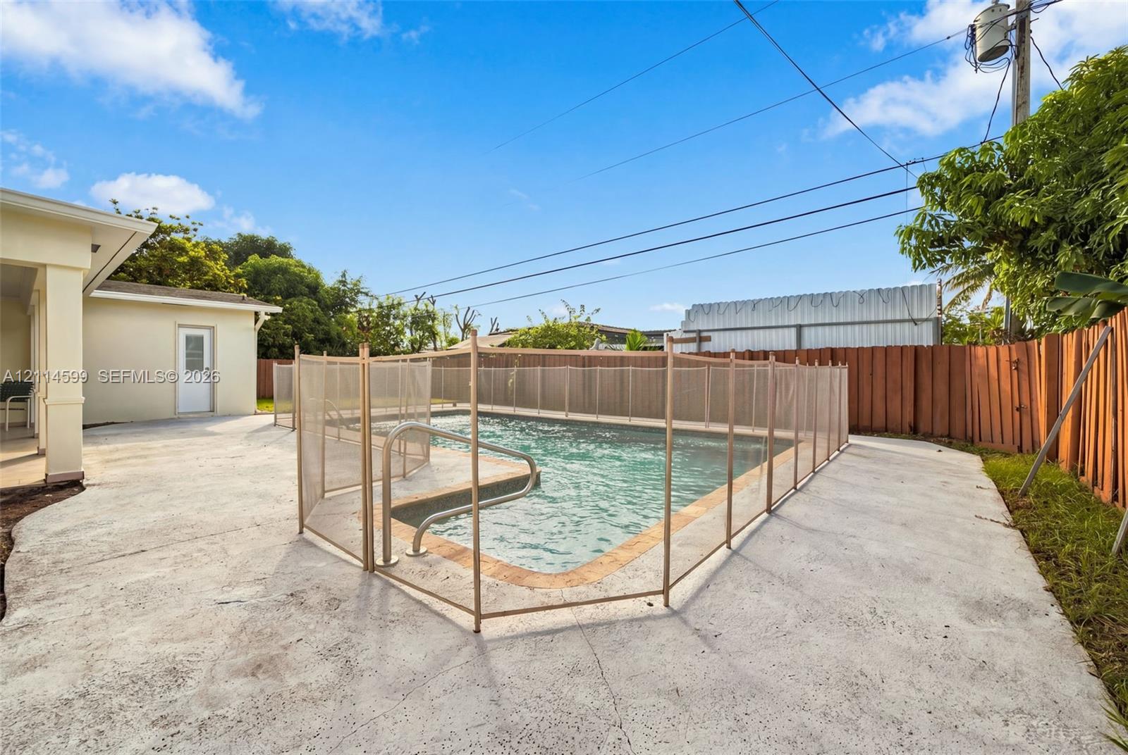 In-ground swimming pool featuring a perimeter safety fence, concrete decking, and surround fencing