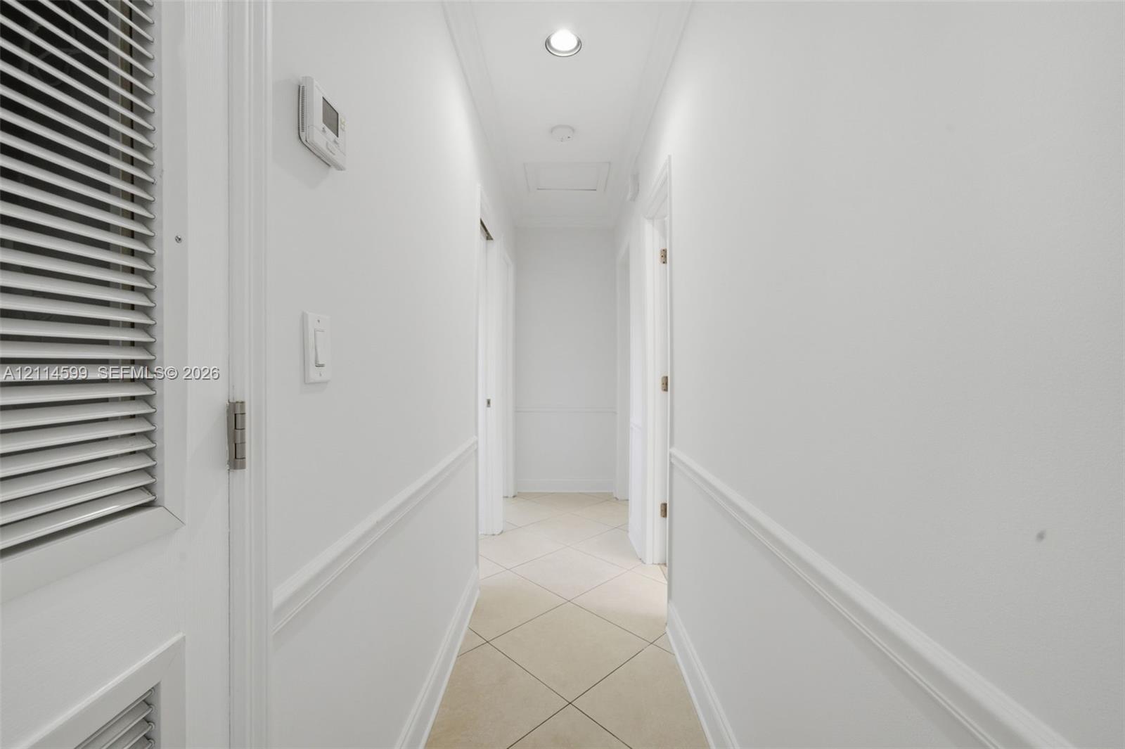 Hallway featuring neutral tile flooring, chair rail molding, and recessed ceiling lighting