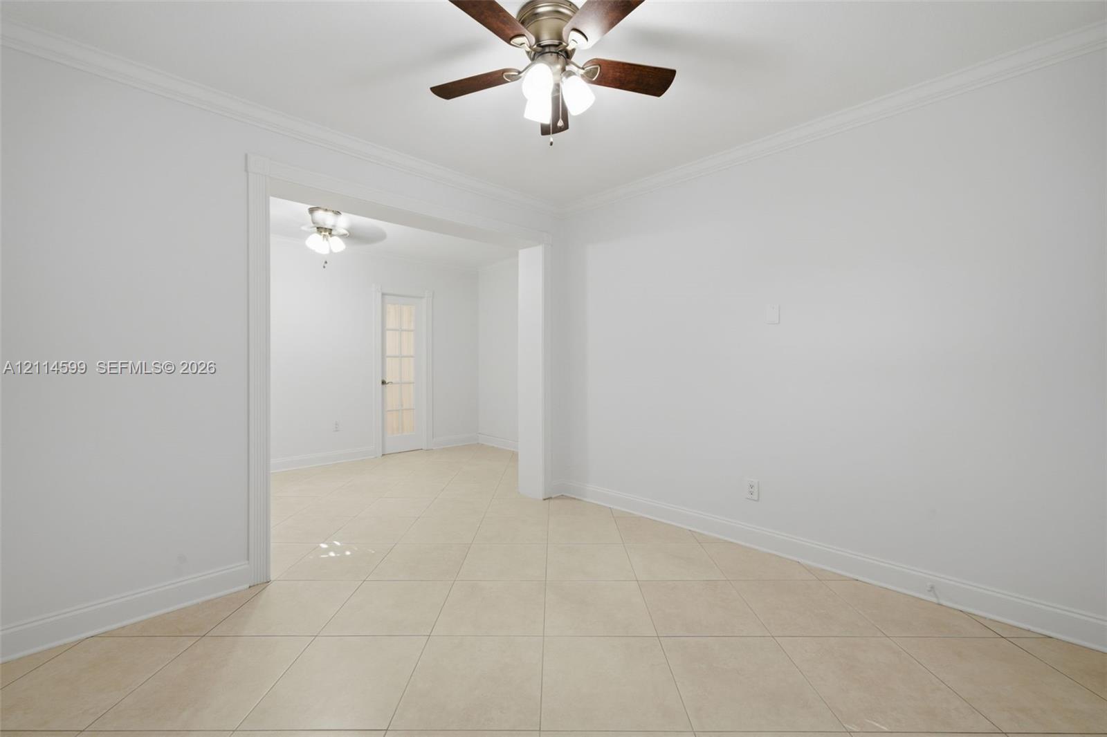 Interior space featuring large-format ceramic tile flooring, crown molding, a multi-light ceiling fan with dark wood-finish blades, and a glass-paneled interior door