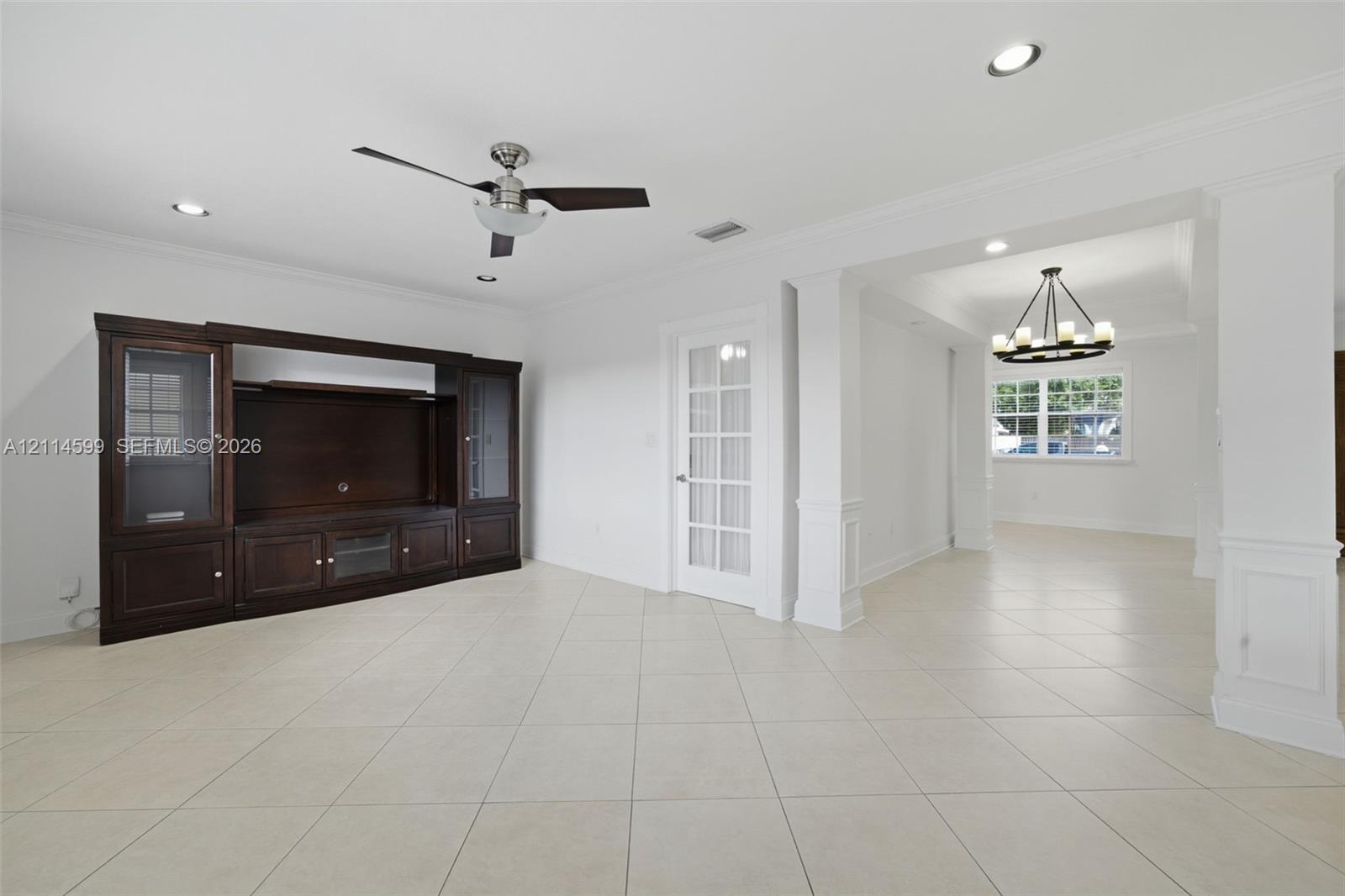 Built-in dark wood cabinetry with glass display panels, ceramic tile flooring, recessed lighting, crown molding, and a French door