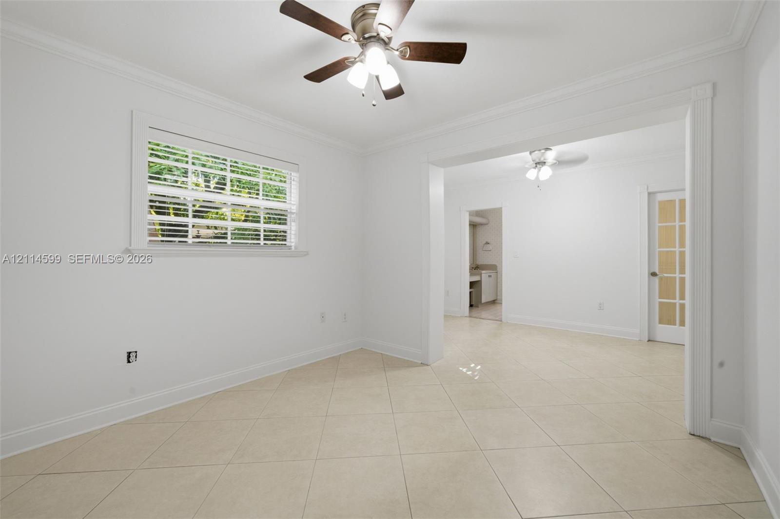Interior space featuring large-format diagonal tile flooring, ceiling fans with integrated light kits, crown molding, and a glass-paneled door