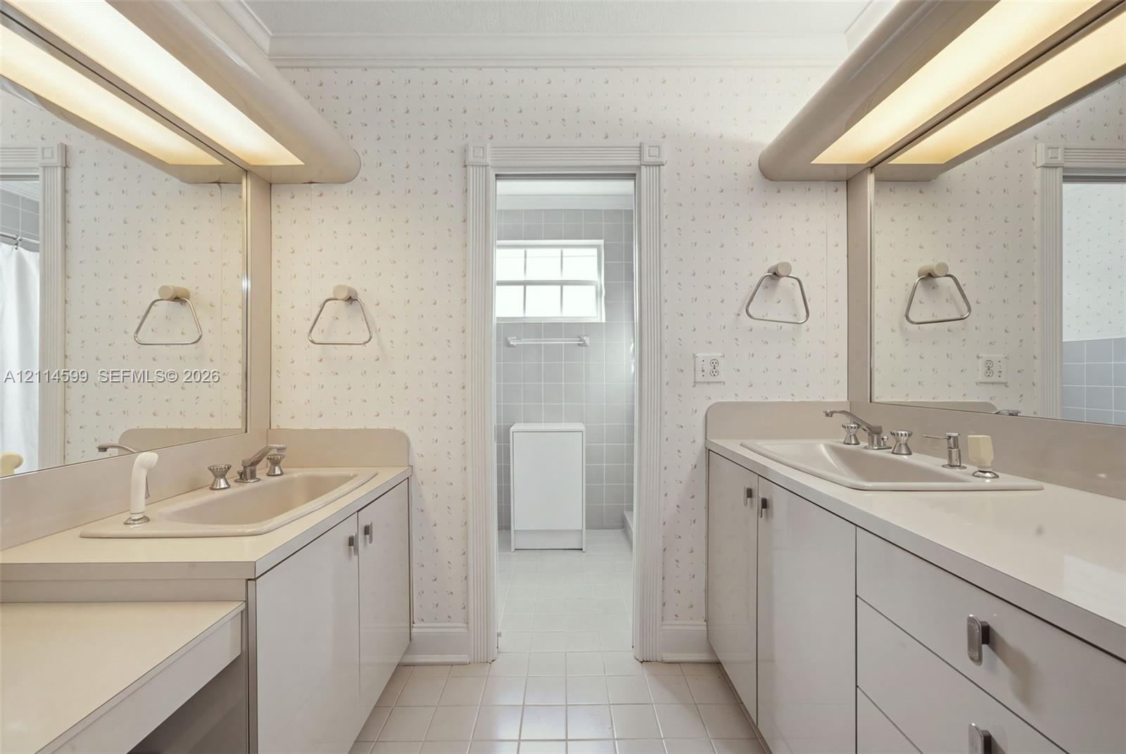 Dual vanity featuring integrated sinks, solid surface countertops, light-toned cabinetry, and wall-mounted linear light fixtures