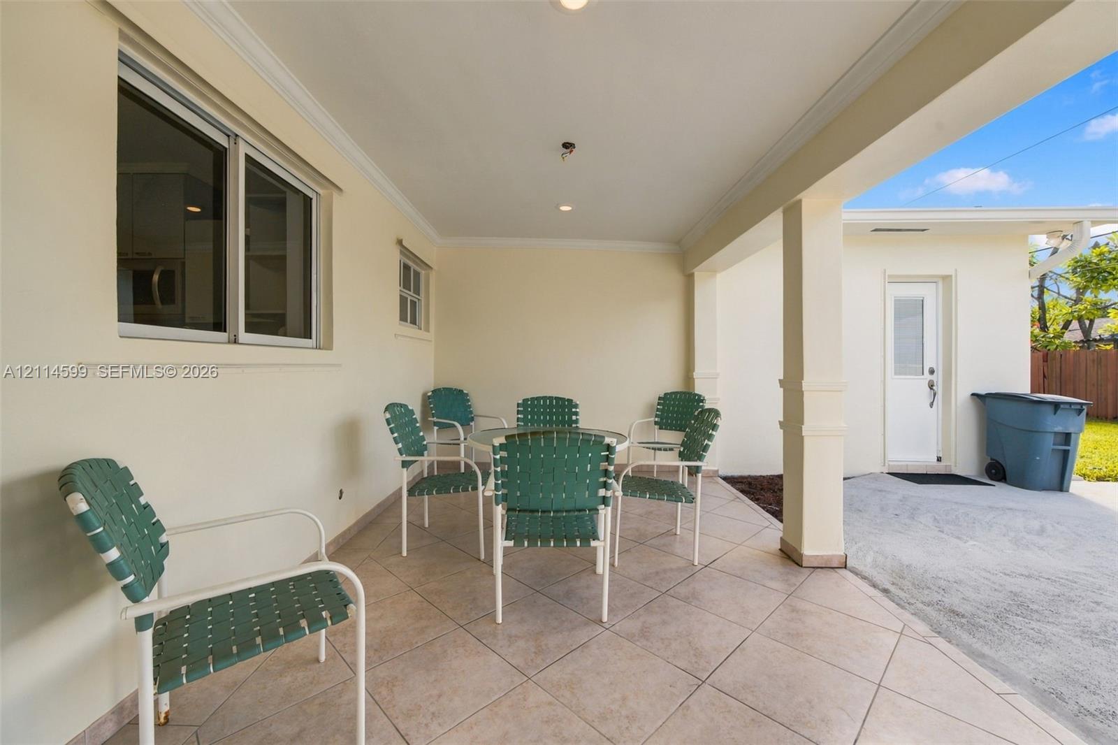 Covered patio featuring large-format ceramic tile flooring, crown molding, recessed lighting, and a square support column