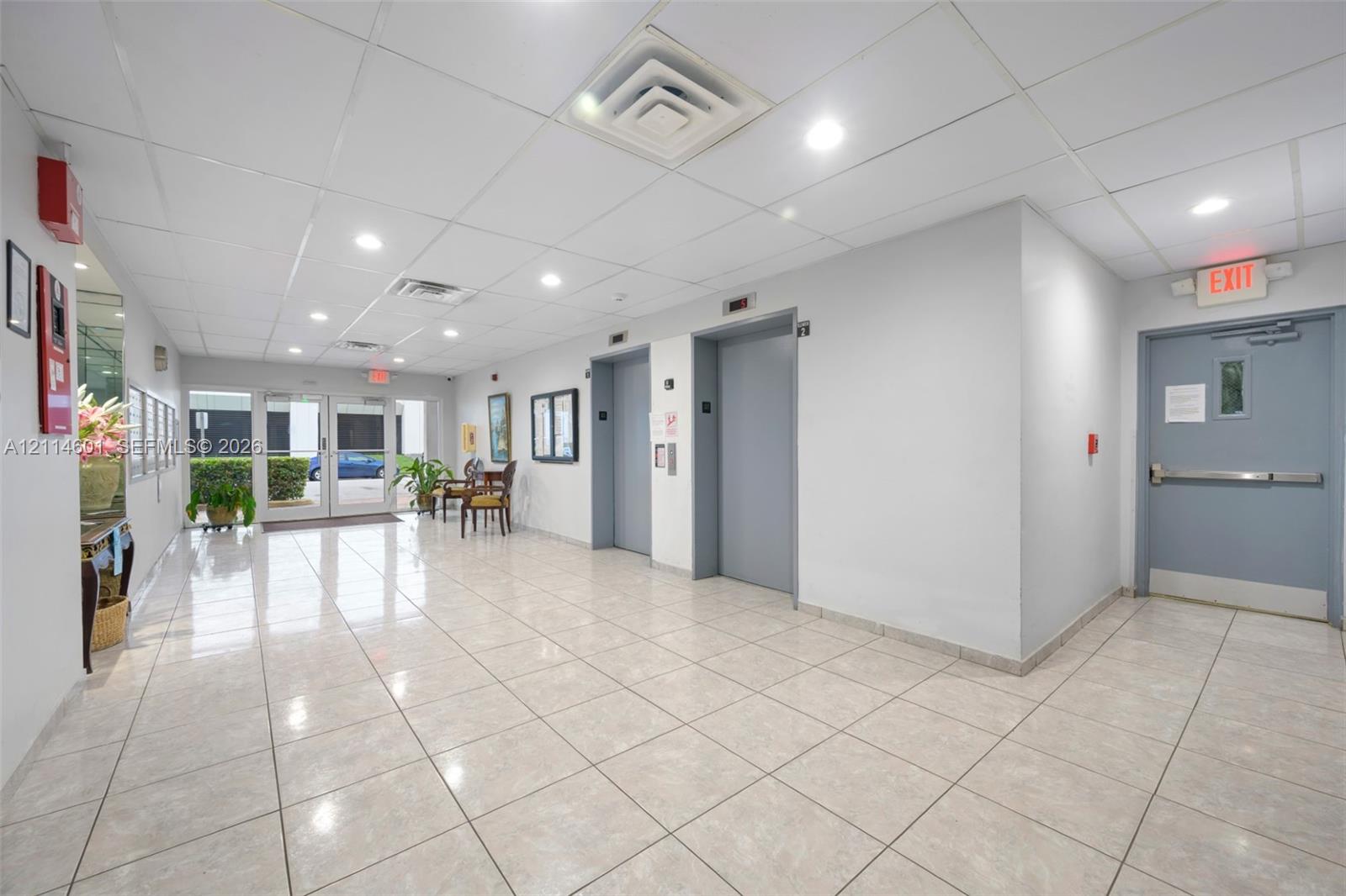 Common area lobby featuring tile flooring, recessed lighting, drop ceiling, and dual elevator access