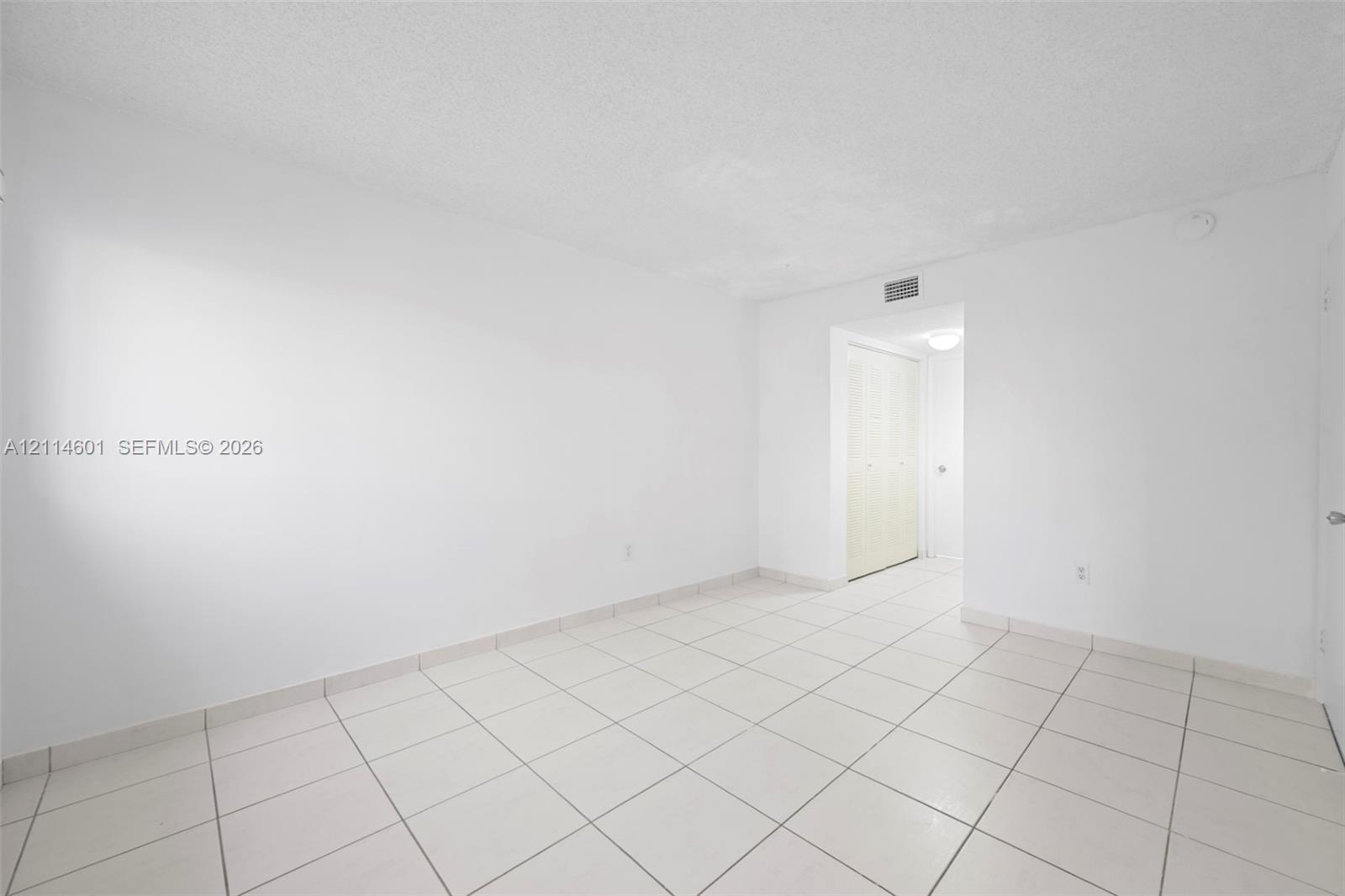 Neutral interior featuring large-format ceramic floor tiling and a built-in closet with bi-fold doors