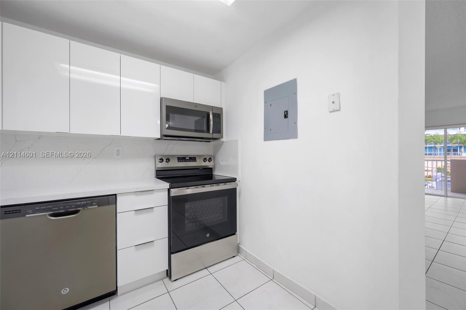 Kitchen featuring gloss-finish cabinetry, stone-surface countertops, tile backsplash, and stainless-steel appliances including a built-in microwave and range