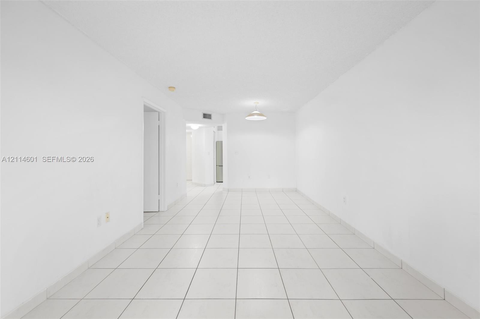 Interior area featuring white walls, neutral tile flooring, and a central pendant light fixture