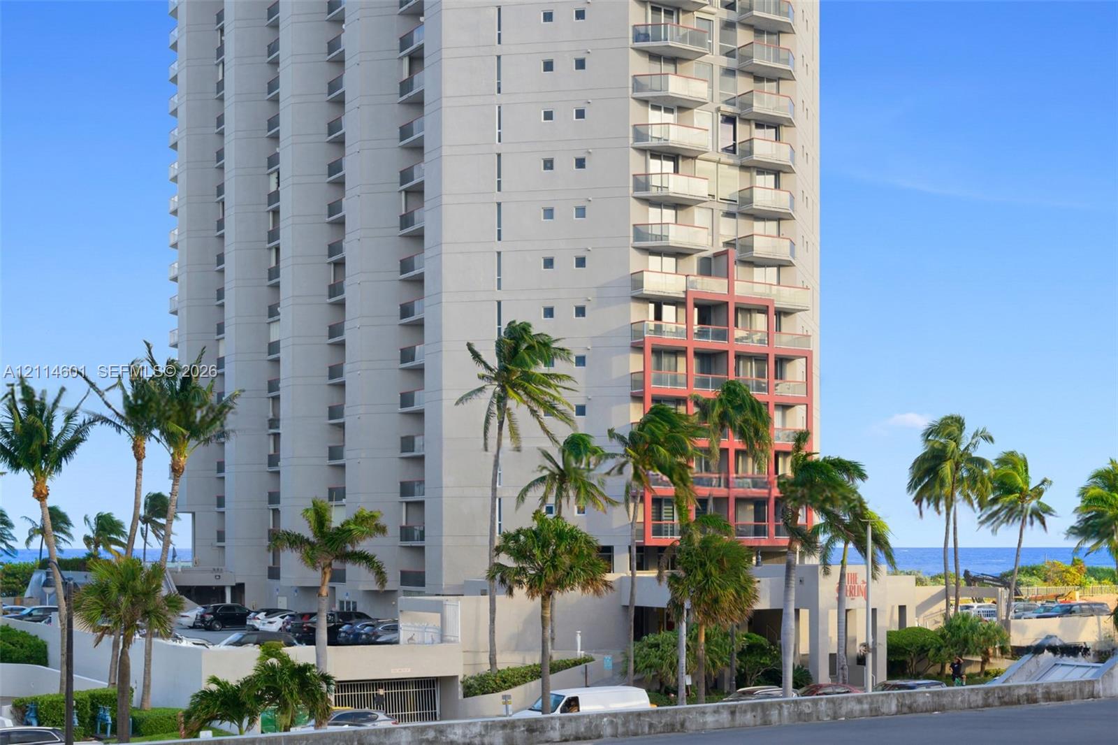 High-rise exterior featuring individual balconies, exterior accent detailing, a covered entrance, and mature palm trees
