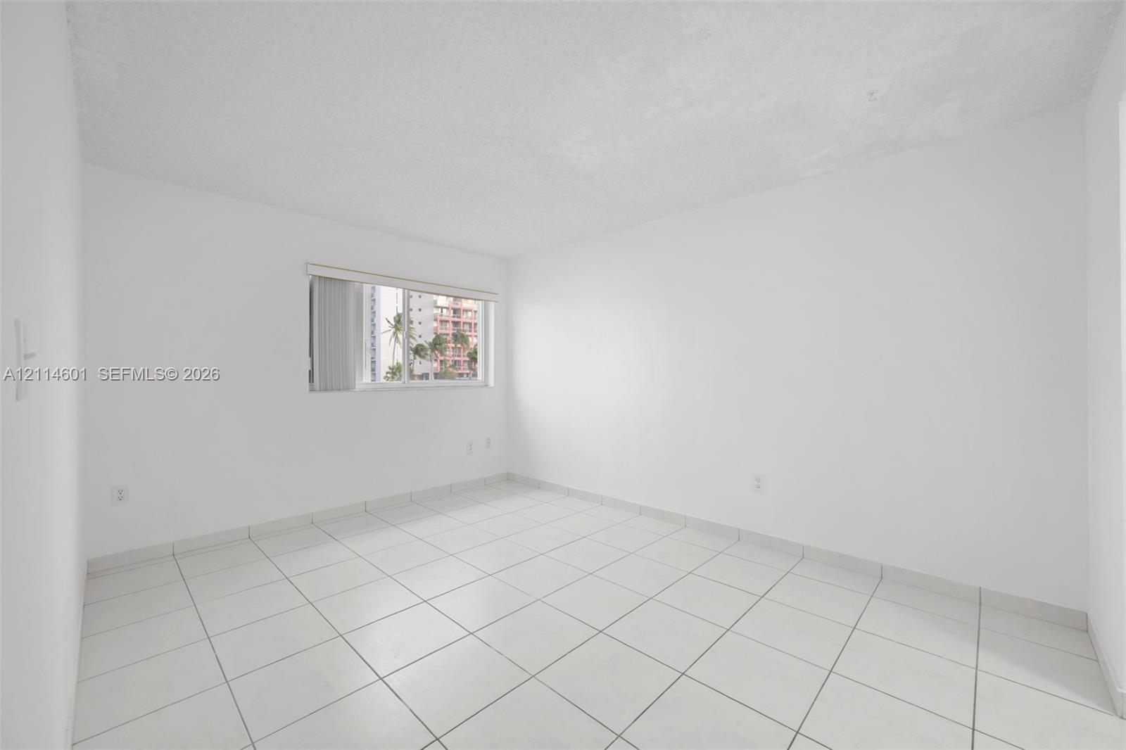 Neutral room featuring white walls, square tile flooring, and a single-pane window with adjustable blinds