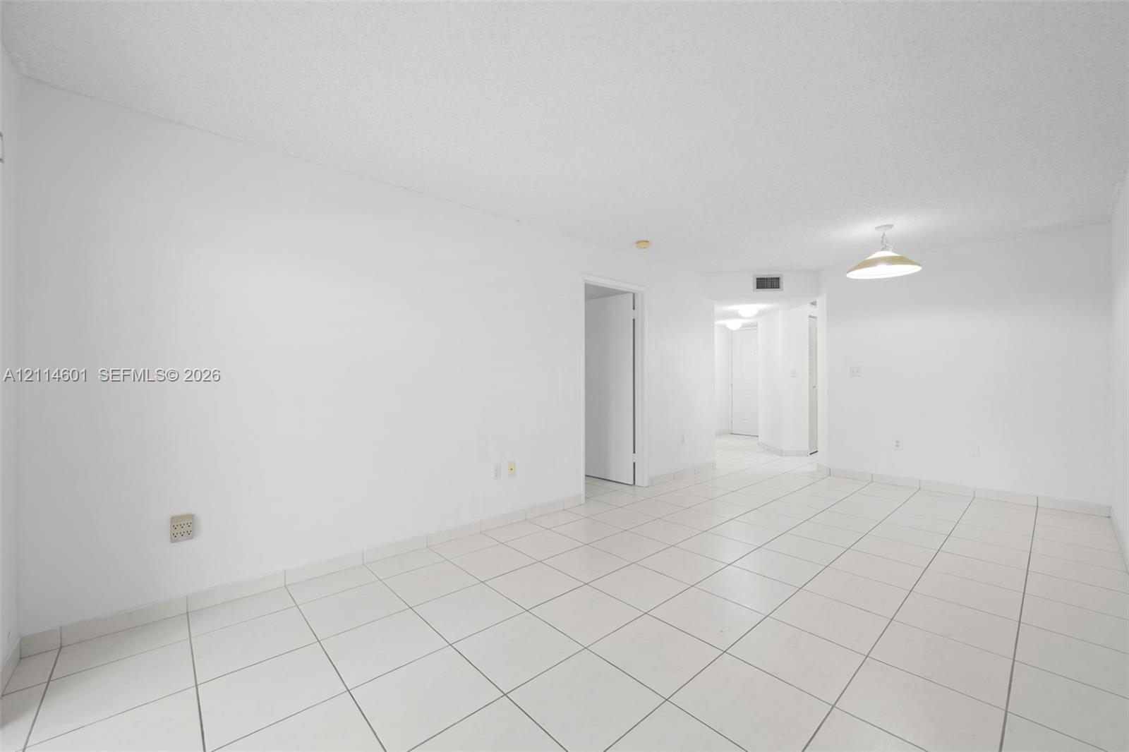 Open interior space featuring light-toned tile flooring, white walls, and a bowl-style pendant light fixture