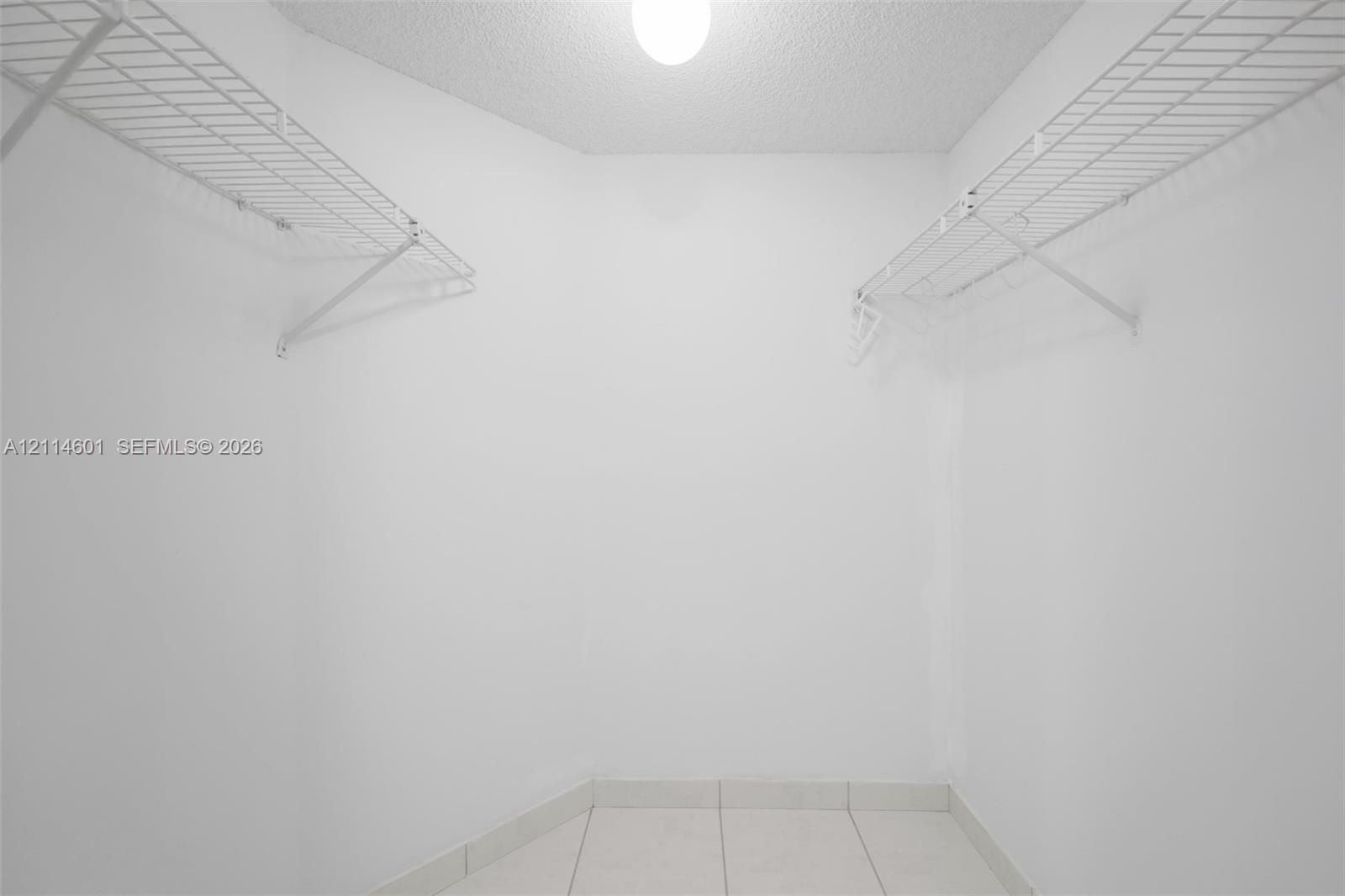 Storage area featuring white walls, white tile flooring, and dual tiers of white wire shelving