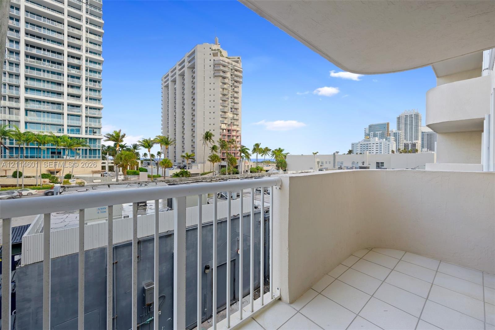 Covered balcony featuring white tiled flooring and a white metal railing