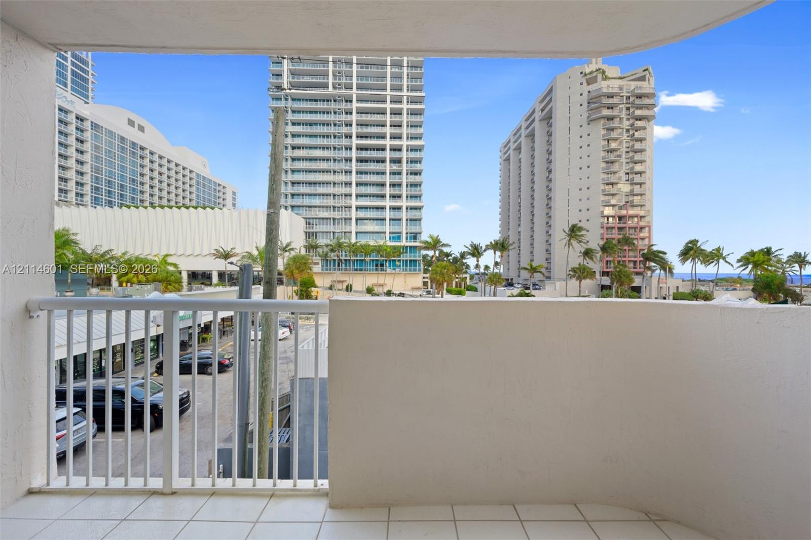 Private balcony featuring tiled flooring, a solid concrete perimeter wall, and a white metal safety railing
